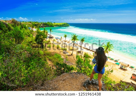 Beautiful latin woman in blue bikini on tropical beach. Portrait of happy young woman smiling at sea. Brunette tanned girl in swimwear enjoying and walking on beach.