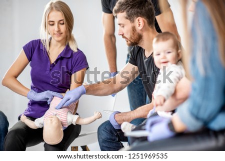 Group of people during the first aid training with instructor showing on manikin how to do artificial respiration for the baby Royalty-Free Stock Photo #1251969535