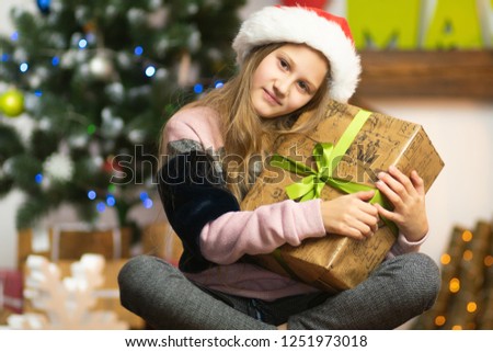 Beautiful girl sitting on a sled near a Christmas tree, a fireplace and a star with light bulbs