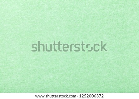 Light green matte background of suede fabric, closeup. Velvet texture of seamless mint woolen felt.