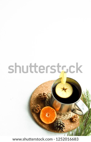 Hot flavored drink with mandarin, apple and lemon on a cork stand.
