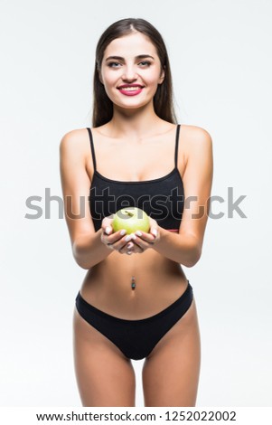 Fit and sporty girl in white underwear. Beautiful and healthy woman eating green apple over grey background. Sport, fitness, diet, weight loss, nutrition and healthcare concept.