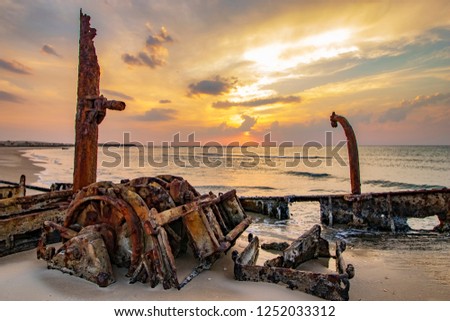 A ship sunk on the beach at sunset	