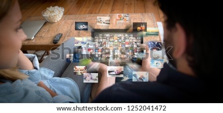 Couple using tablet for watching VOD service. Video On Demand television with abstract flying images Royalty-Free Stock Photo #1252041472