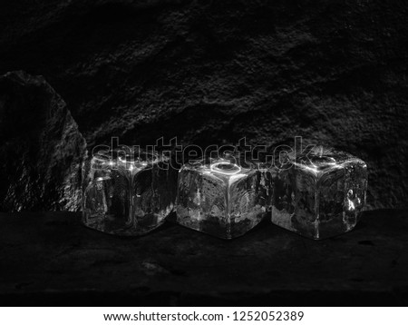 Ice Cubes of Frozen Water Showing a Square Shape of the Liquid, Displayed on a Rock and Blurred Stone Background.