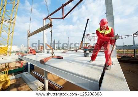 builder worker in safety protective equipment installing concrete floor slab panel at building construction site