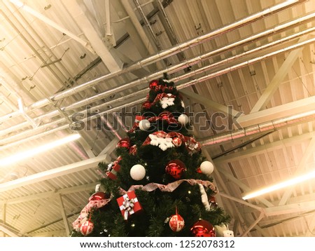 Festive green beautiful elegant Christmas tree with balls for the New Year on the background of the ceiling with metal ventilation pipes in the loft style. Concept: Christmas at an industrial plant.
