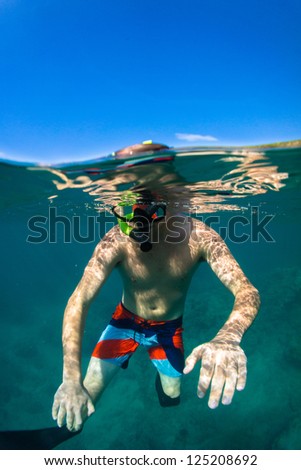 Young man free diving and snorkeling on a lively reef