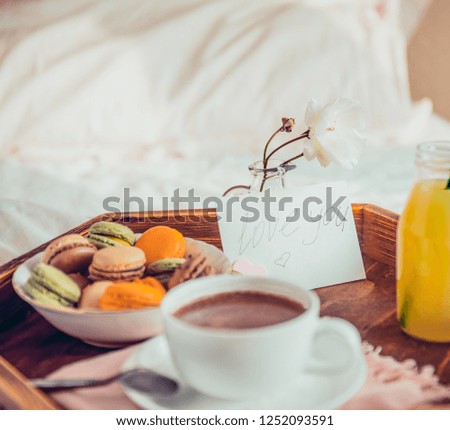 Breakfast in bed with i love you text on a note. Cup of coffee or cocoa, juice, macaroons, rose flower on wooden tray. Romantic breakfast in bed. Birthday, Valentine's day morning. Square. Copy space