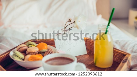 Breakfast in bed with i love you text on a note. Cup of coffee, juice, macaroons, rose flower on wooden tray. Romantic breakfast in bed. Birthday, Valentine's day morning. Wide banner. Copy space