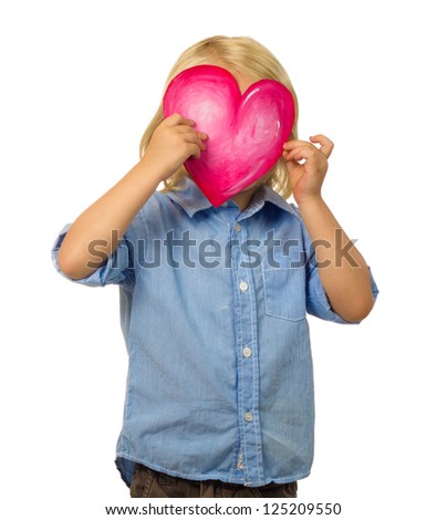 Cute young child hiding his face behind a pretty love heart. Isolated on white.