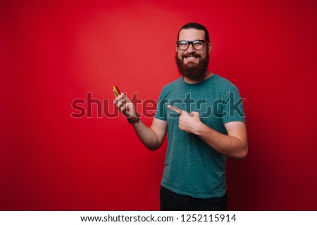 Smiling bearded man pointing to smartphone in hand