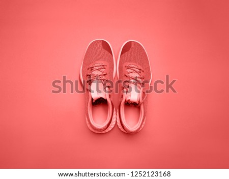 Trend photography on the theme of the new color of the year 2019 - Living Coral. Pair of living coral sport shoes on background