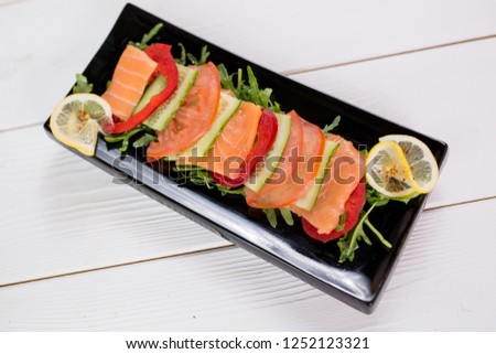 Vegetables with fish slices on black plate. Healthy food concept. Photo for menu