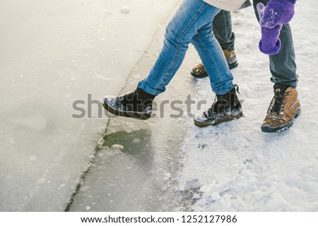 Trying the danger of the foot, testing the thin ice near the shore. A pair of lovers walk with a walk along a frozen lake to press foot on the ice. Royalty-Free Stock Photo #1252127986