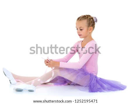 Cute little girl ballerina wears ballet shoes. The concept of learning to dance. Isolated on white background.