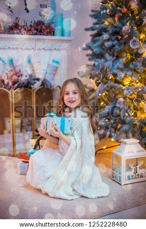 Little girl under the Christmas tree. A girl with gifts under the tree in anticipation of magic, a gift from Santa Claus