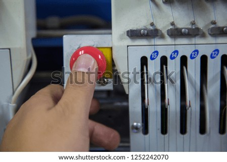 Man hand Press Red Emergency button of embroidery machine,stop button for industrial machine, Emergency Stop for Safety.