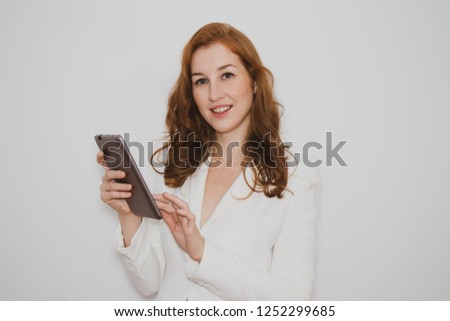 businesswoman in a white jacket surfs the Internet on a tablet and looks into the camera on a white background, copy space