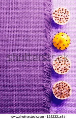Fresh pieces of lemon with cloves  on burlap. Creative minimalistic food concept.Trend color proton purple.Copy space.