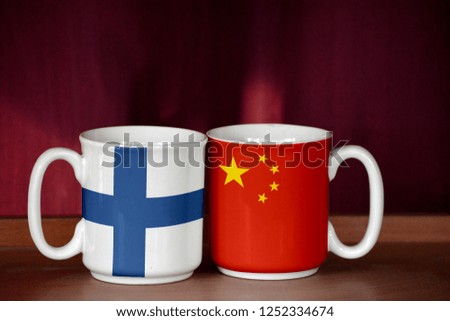 China and Finland flag on two cups with blurry background