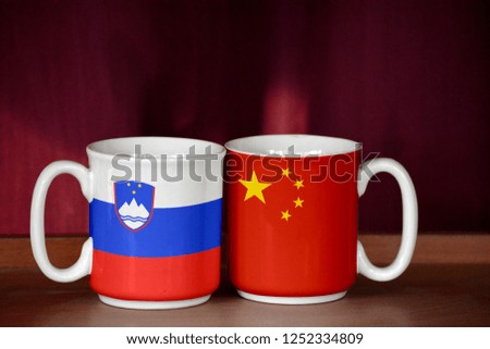 China and Slovenia flag on two cups with blurry background