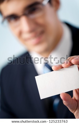 Happy smiling businessman showing blank business card, at office. Focus on hand.