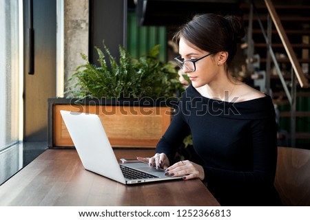 Focused business woman sit on cafe working on laptop, concentrated serious female working with computer and notebook in coffee shop, freelancer, studying online, browse internet, checking bills Royalty-Free Stock Photo #1252366813