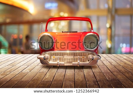 Old antique car shape AM FM stereo cassette player on wood table top with blur background