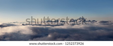 A long panorama of the peaks of the Caucasus range towering above the clouds