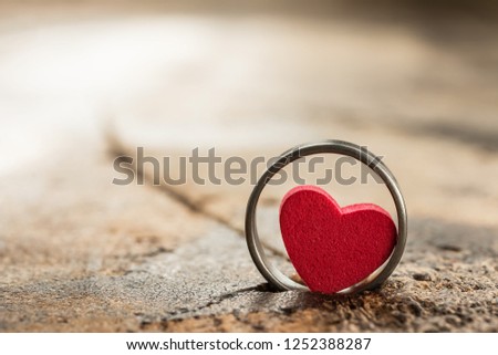 A photo of Small heart in the ring on old wood table background. valentine concept. Selective and soft focus.