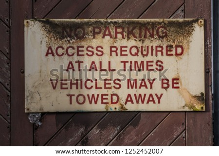 old rusty warning sign - no parking, access required at all times - vehicles may be towed away 