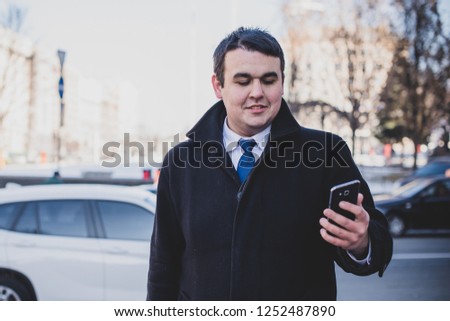 View of  plump guy using smartphone, Young urban businessman professional on smartphone walking in street using app texting sms message on smartphone