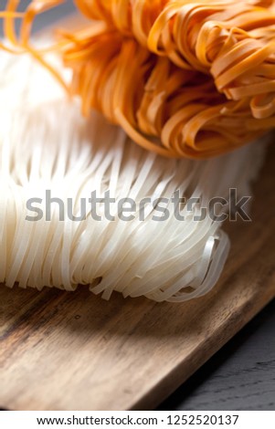 Raw rice flour noodles on wooden background , photographed overhead on dark wood with natural light (Selective Focus, Focus on the top of the noodles)