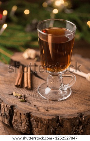 Christmas and Thanksgiving mulled apple cider with spices: cinnamon sticks, cloves, anise on white table with traditional rustic Christmas background flowers arrangement, Autumn and winter drink.