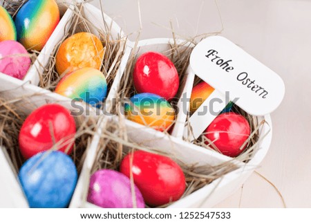 Multicolored easter eggs on vintage painted wooden background. German TEXT Happy Easter.
