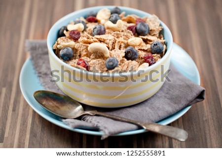 Bowl of homemade granola with yogurt and fresh berries on wooden background from top view.