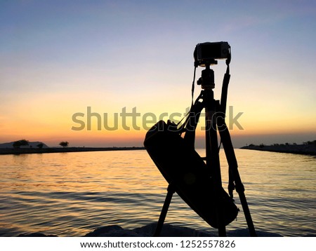 Silhouette Setting Camera with tripod over sun rising near the beach,Thailand.