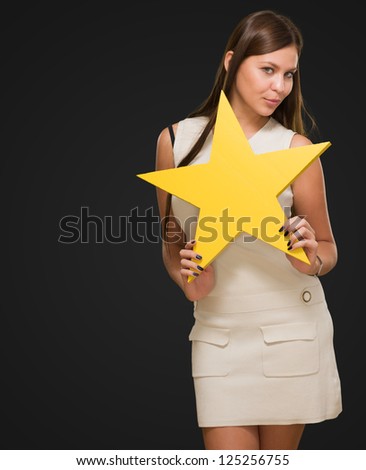 Portrait Of Young Woman Holding Yellow Star against a black background