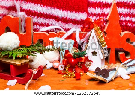 festive christmas wooden background with toy deer, house, sledge, ski, red scarf, snow, and text Christmas