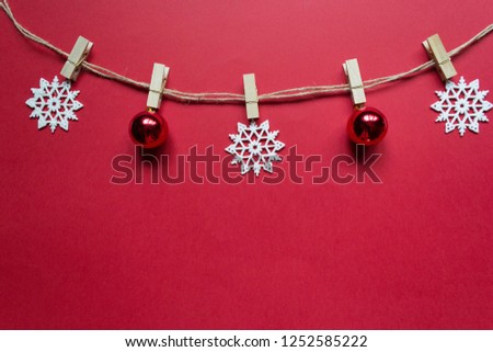 Christmas composition on a red background. Garland made of white snowflakes and red candies, bows, balls and fir tree branches on red background. Christmas, winter, new year concept. Flat lay