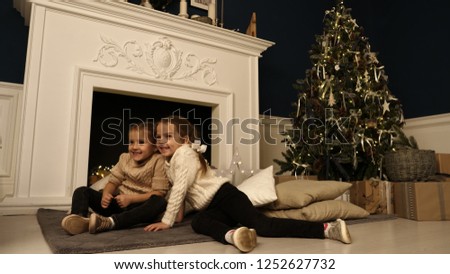 Two little girls pose during Christmas photo session. Studio shooting before the holidays.