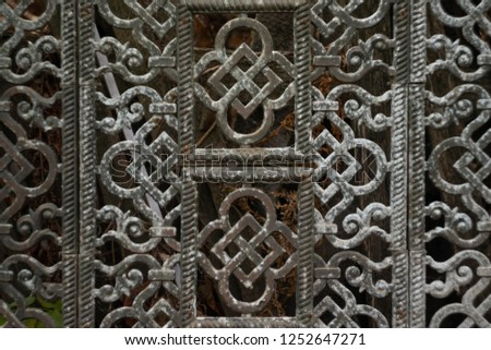 An old metal grille. Composed of patterned openwork plates with oriental ornament. The gray plaque of antiquity