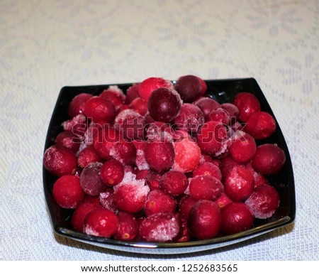 Frozen cranberries in a black bowl table covered with white cloth