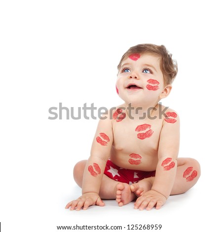Picture of happy kid covered with red kisses, adorable baby boy sitting in studio isolated on white background, Valentine day, lovely small child with lipstick print on the body, love concept