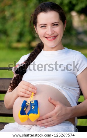 Happy pregnant woman with boxing gloves in the park outdoors