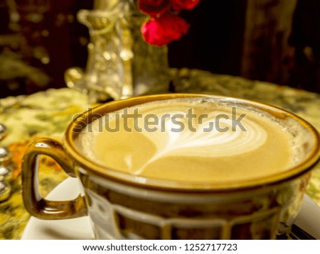 luxurious classical cafe, table with a vase and red flowers, view of a heart composed of coffee. Old pre war antique furniture, shabby chic exterior. Vintage style. Brown cup of coffee and heart shape