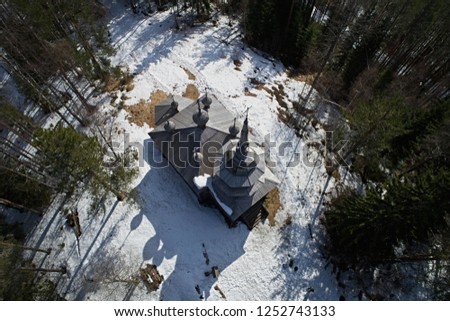 Aerial view of the old orthodox church in the forest in winter. Photo of northern wooden architecture from the drone
