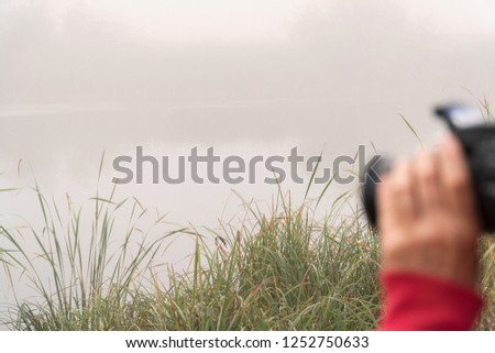 Woman photographer photographs the fog on the lake. Selective focus