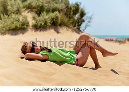 Teenage girl lying on the sandy beach on a hot summer day